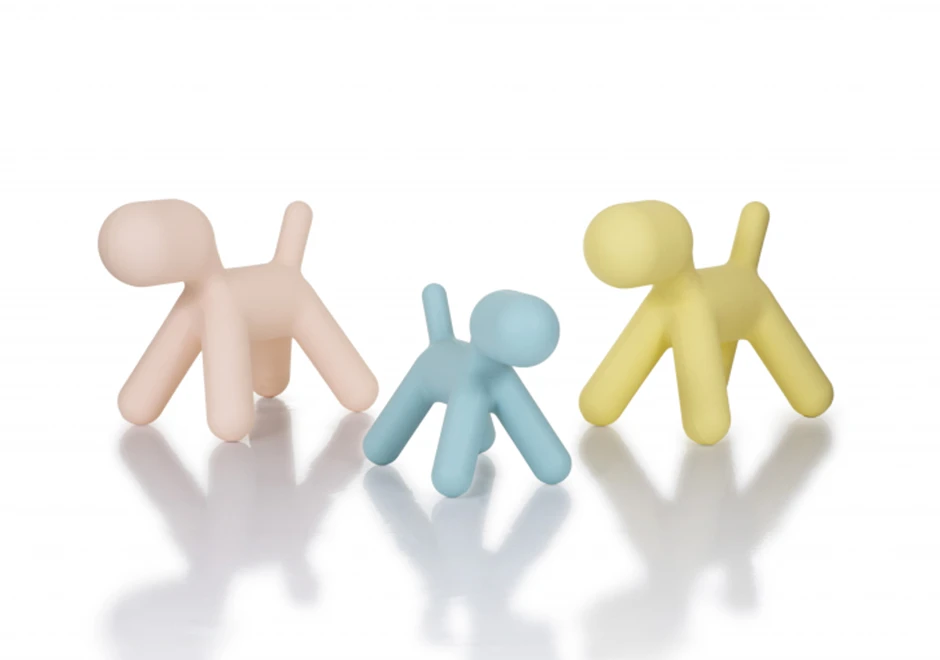 Três bancos de design em formato de cachorro em polietileno azul, rosa e amarelo, visto de lado em um fundo branco.