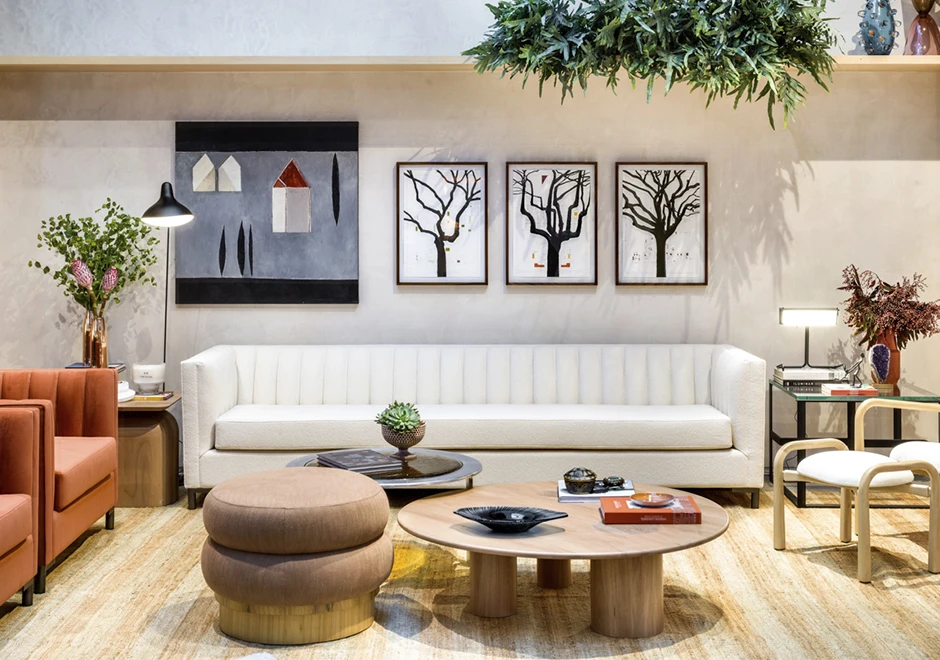 Banco de madeira Freijó, estofado em tecido bege, visto de frente, em uma sala grande e moderna.