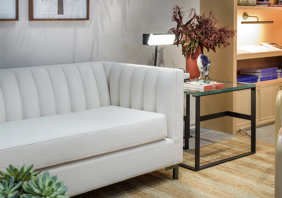 Detalhes de sofá de design em ondas, com estrutura de madeira, pés em metal, estofado em tecido branco, visto de lado, em uma sala moderna.