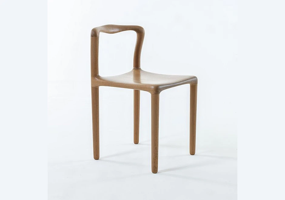 Cadeira assinada de madeira Tauari natural, vista de lado, em um fundo branco.