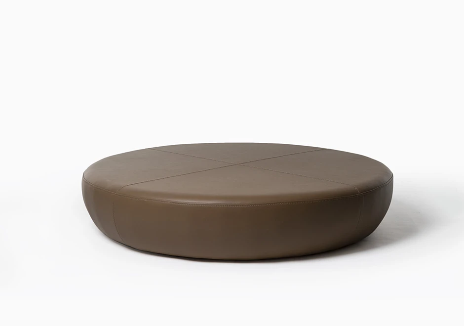 Pufe com estrutura de madeira, e acabamentos diferenciados em couro marrom, vistos de frente em um fundo branco.