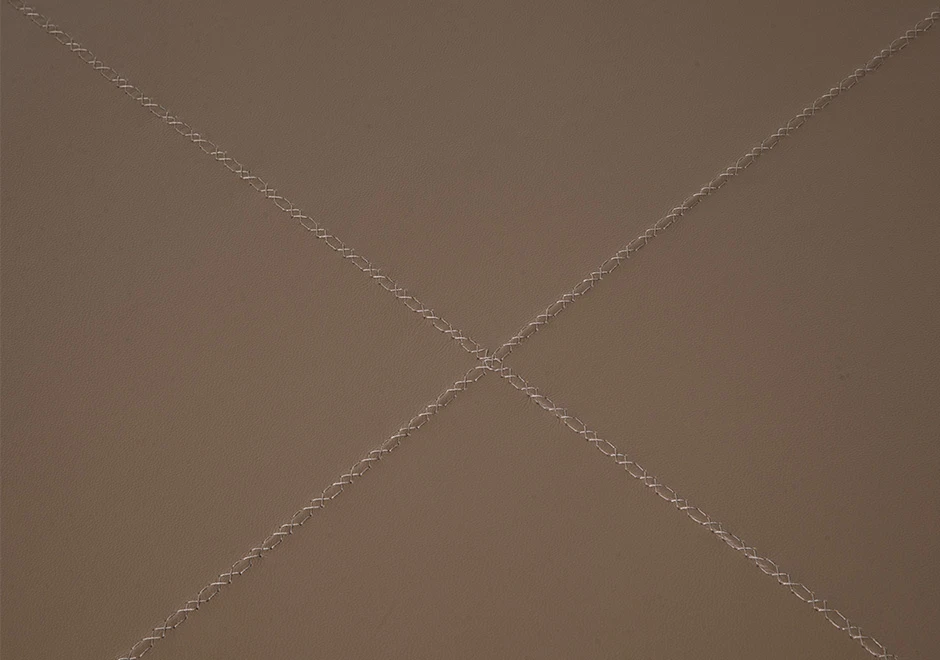 Detalhe de costura de pufe com estrutura de madeira, e acabamentos diferenciados em couro marrom, vistos de frente em um fundo branco.