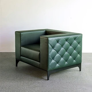 Poltrona assinada GABRIELLE com estofado de couro natural com acabamento matelassê em losango, pés de aço carbono e pintura eletrostática