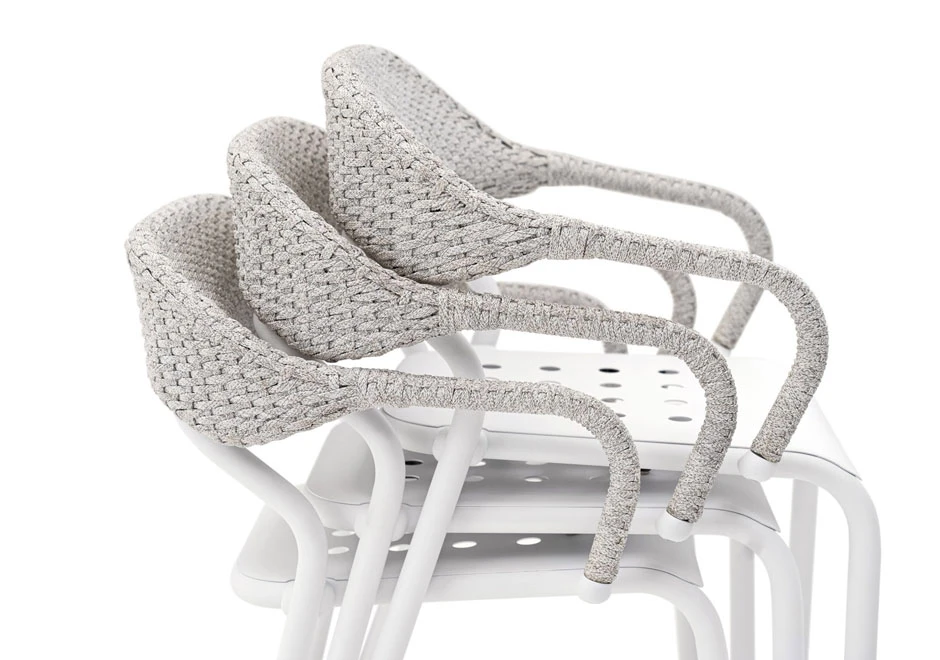 Cadeiras de design com estrutura de alumínio e encosto de fibra sintética trançada a mão na cor branco, empilhadas em um fundo branco.