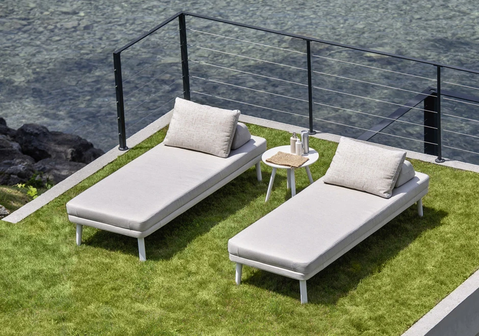 Duas chaise longue com estrutura de alumínio com pintura eletrostática, pés em alumínio pintado ou madeira Iroko natural, tecido na cor bege, visto de cima em uma area externa.