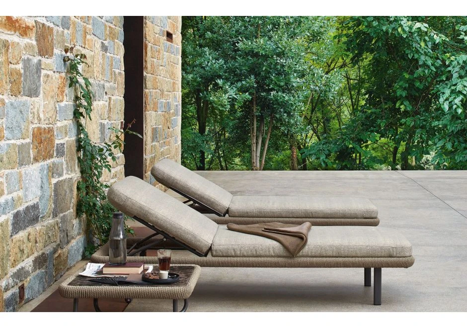 Duas chaise longue com estrutura e rodinhas em alumínio pintado, corda de fibra sintética de cânhamo, almofada em tecido bege, vistas de lado em uma area externa.