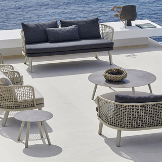 Sofá para área de lazer, na cor azul, com encosto em fibra na cor cinza e pés de aluminio, com duas poltronas de mesmo modelo, visto de cima em uma area externa.