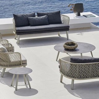 Sofá para área de lazer, na cor azul, com encosto em fibra na cor cinza e pés de aluminio, com duas poltronas de mesmo modelo, visto de cima em uma area externa.