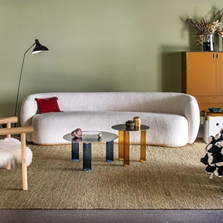 Sofá curvo, estofado em tecido branco, visto de frente, em uma sala aconchegante.