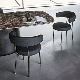 Duas cadeiras de design com estrutura tubular de aço com acabamento em pintura eletrostática preta em volta de uma mesa de jantar.