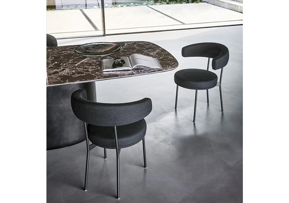Duas cadeiras de design com estrutura tubular de aço com acabamento em pintura eletrostática preta em volta de uma mesa de jantar.