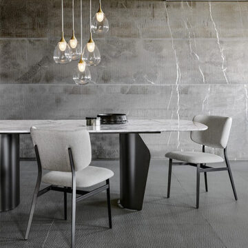 Duas cadeiras assinadas com estrutura de aço com pintura eletrostática e estofada em tecido branco, em volta de uma mesa de jantar.