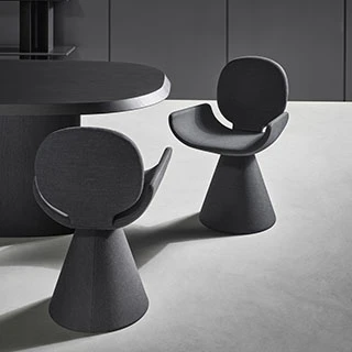 Duas cadeiras de design com estrutura de aço cônica e assento e encosto em espuma de poliuretano, estofada em tecido cinza, vistas uma de frente para a outra em uma sala.