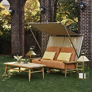 Sofá de design para area externa, cintas elásticas e tela de polivinil, na cor creme e laranja, de lado, com o dossel aberto, em uma area externa.