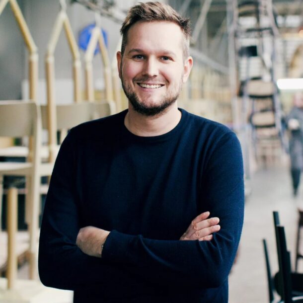 Sebastian Herkner veste blusa em azul marinho e posa de braços cruzados.