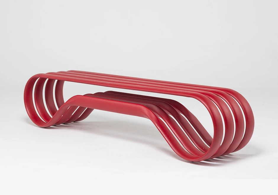 Banco de alumínio pintado de vermelho, visto de lado, em um fundo branco.