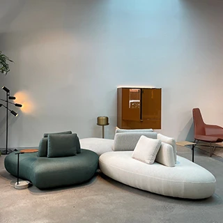 Sofá Pedras modular, com estrutura de madeira, com almofadas decorativas, estofado em tecido branco e azul, visto de lado em uma sala moderna.