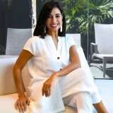 Roberta Banqueri veste branco enquanto posa para foto em ambiente luxuoso.