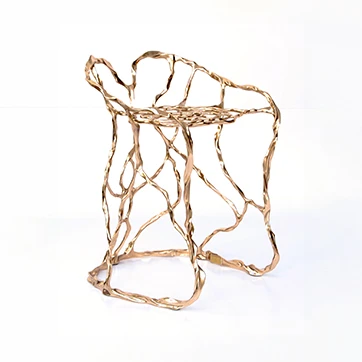 Banco de design em bronze polido ou natural, visto na diagonal em um fundo branco.