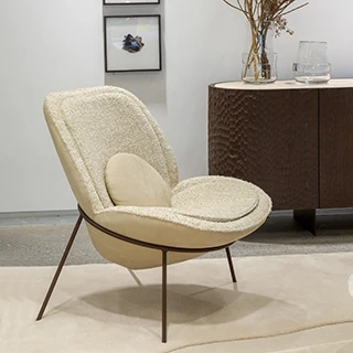 Vista lateral da poltrona Flor, mostrando a estrutura de aço carbono e a forma arredondada da almofada decorativa.