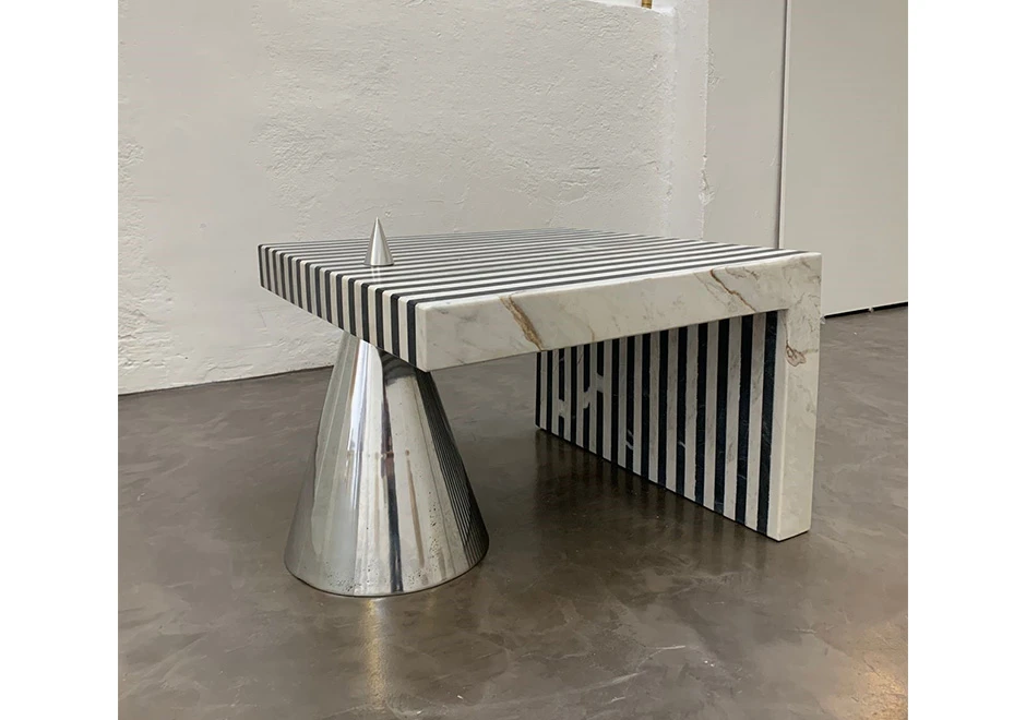 Vista frontal da mesa de apoio Farol, com tampo redondo em mármore preto All Saints e base em forma de cone em alumínio polido