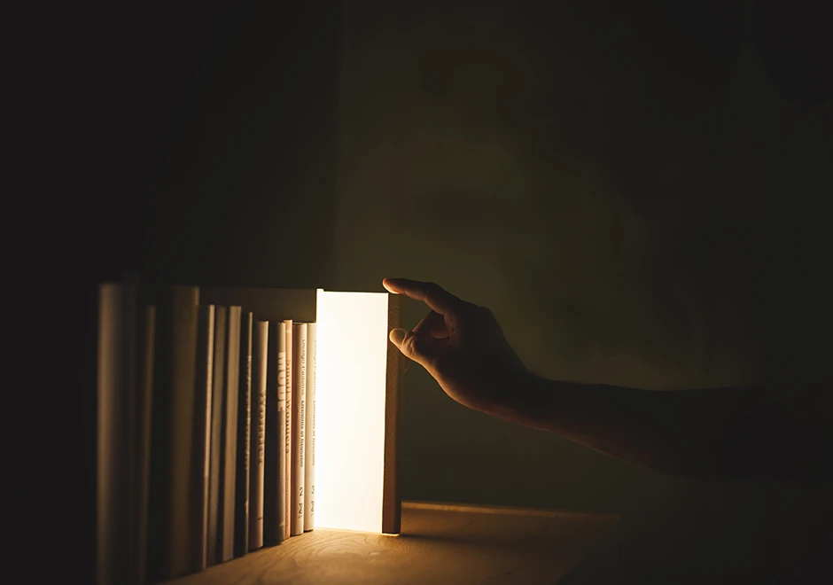 Luminária de mesa Night Book sendo puxada da capa, exibindo o mecanismo de acendimento.