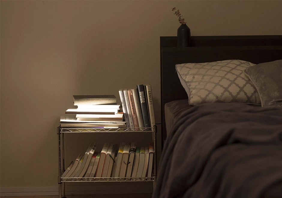 Luminária de mesa Night Book acesa em um ambiente escuro, destacando a difusão suave da luz.