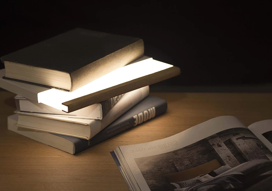 Luminária de mesa Night Book deitada horizontalmente, com ambos os lados emitindo luz.