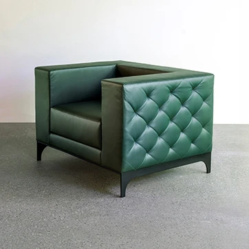 Poltrona assinada GABRIELLE com estofado de couro natural com acabamento matelassê em losango, pés de aço carbono e pintura eletrostática em fundo branco