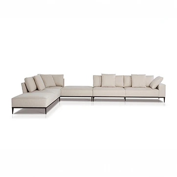 Sofá modular branco, com pés em aço escuro, com diversas almofadas, visto de frente, em um fundo branco