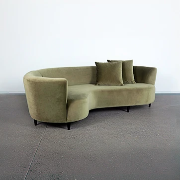 sofá curvo escuro com duas almofadas e cinco pés escuros em um fundo branco.