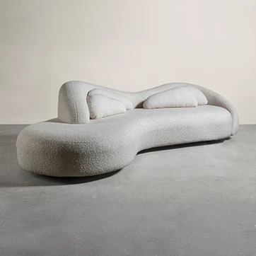 Sofá curvado, branco e com almofadas brancas, também curvadas, visto de frente, em um fundo transparente.