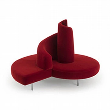 Sofá ilha,com pés em aço cromado e estofado de veludo vermelho, visto de frente, em um fundo branco
