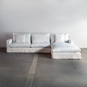 Sofá modular estofado em tecido branco e almofadas decorativas, visto de frente em um fundo branco