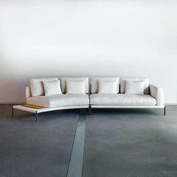 Sofá com escosto com pés de ferro, na cor branca, visto de frente, em um fundo branco.