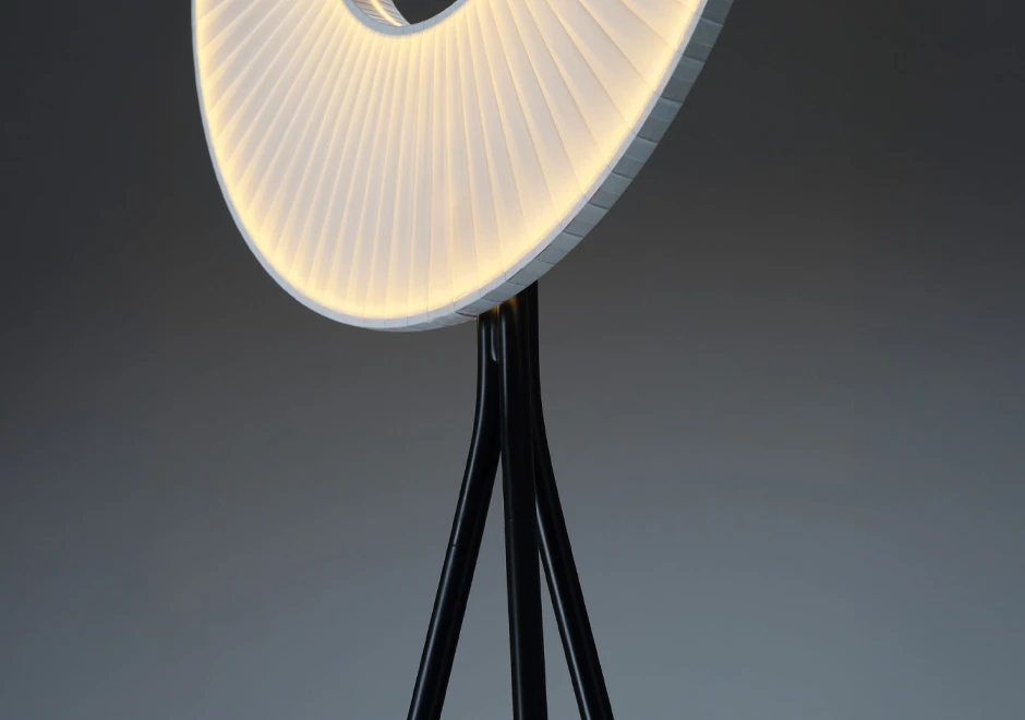 Detalhe da luminária de chão Iris da DCW Éditions, mostrando sua iluminação circular e estrutura tripé preta