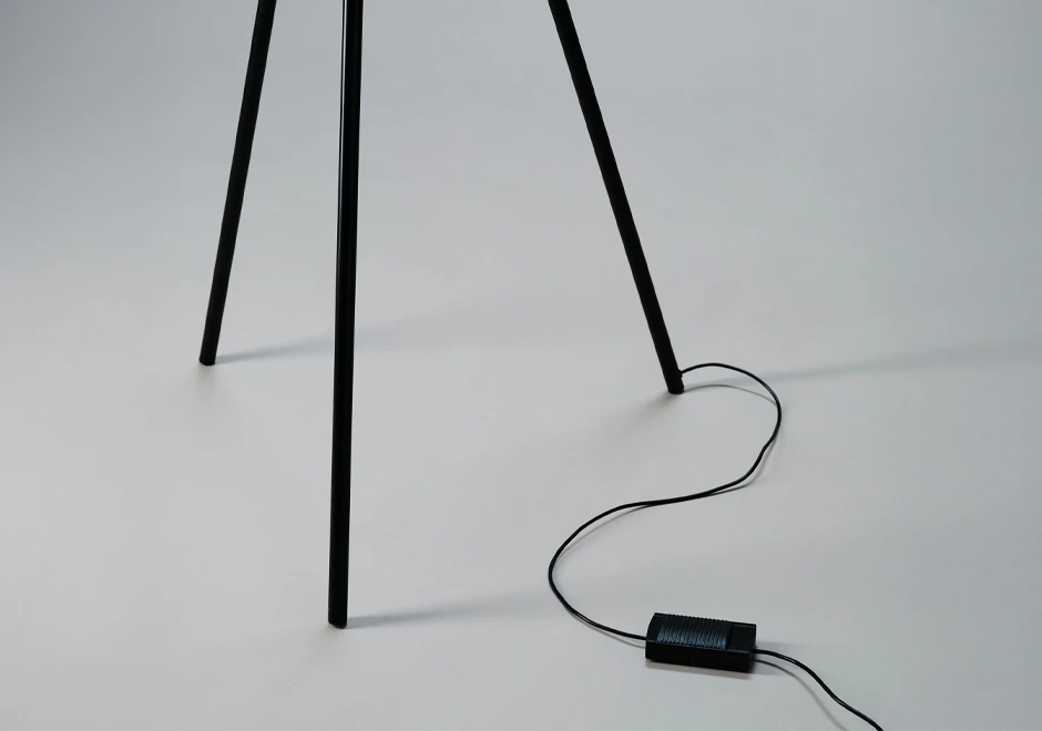 Detalhe da base e do fio da luminária de chão Iris da DCW Éditions, com design minimalista em tripé preto.