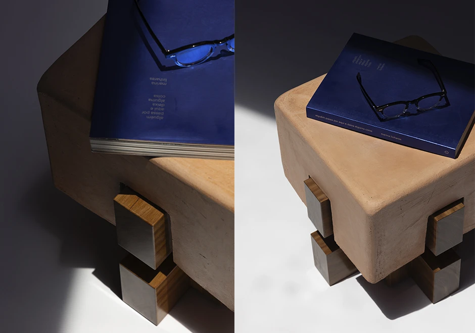 Banco Sertãozinho com livro azul e óculos sobre o assento, destacando a textura da cerâmica artesanal e a base geométrica em madeira maciça.