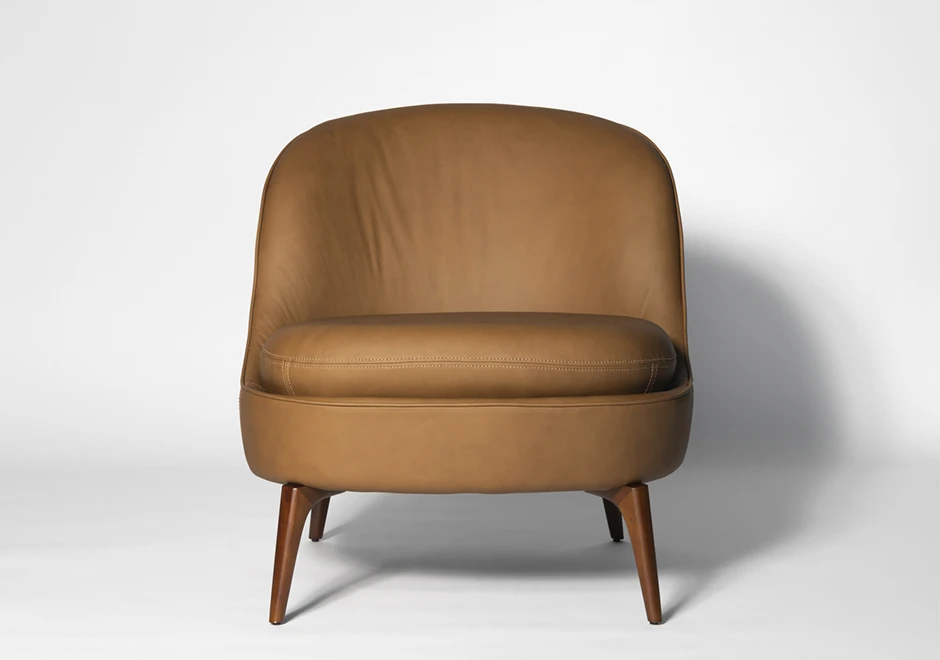 Poltrona Bromélia em couro caramelo com pés de madeira maciça, vista frontal. Design sofisticado e ergonômico para ambientes elegantes.