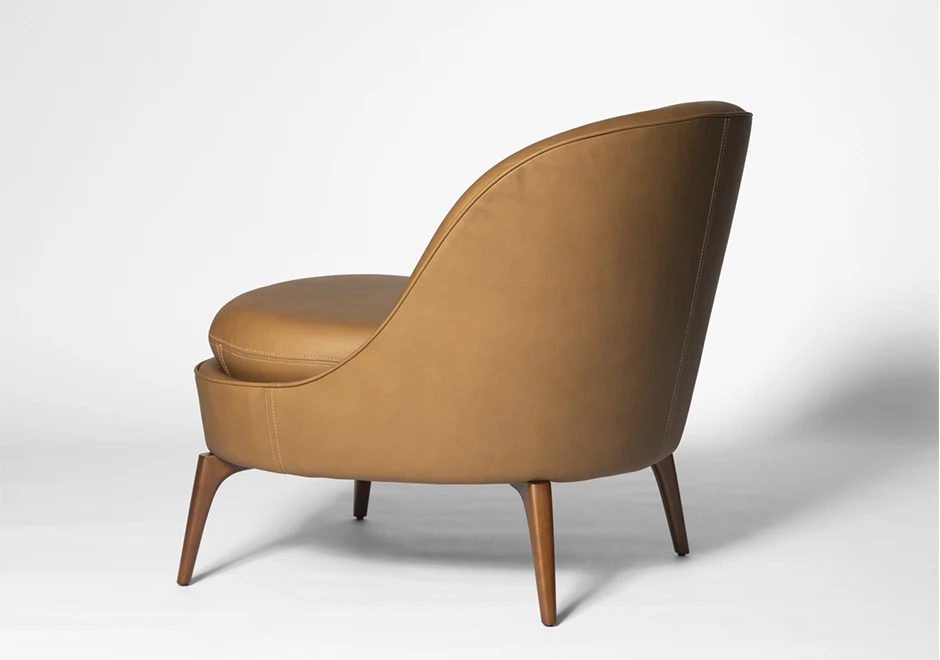 Vista traseira da Poltrona Bromélia em couro caramelo, destacando seu encosto curvado e pés em madeira maciça para um design sofisticado e ergonômico.