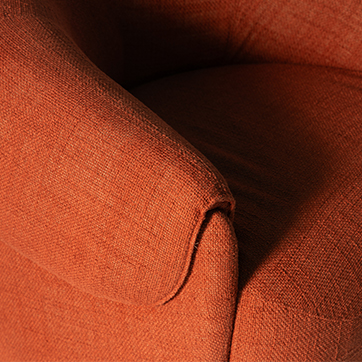 Detalhe do braço da poltrona Orca em tecido terracota, destacando a costura e o estofado volumoso que garantem conforto e sofisticação ao design.