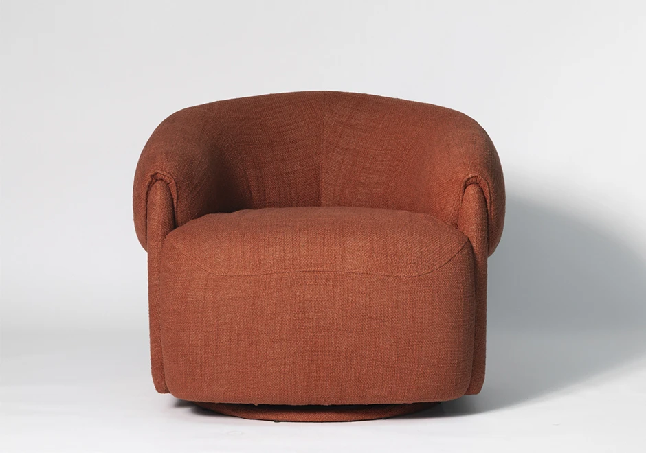 Vista frontal da poltrona Orca em tecido terracota, evidenciando seu design curvilíneo, braços integrados e base giratória oculta para um toque contemporâneo.