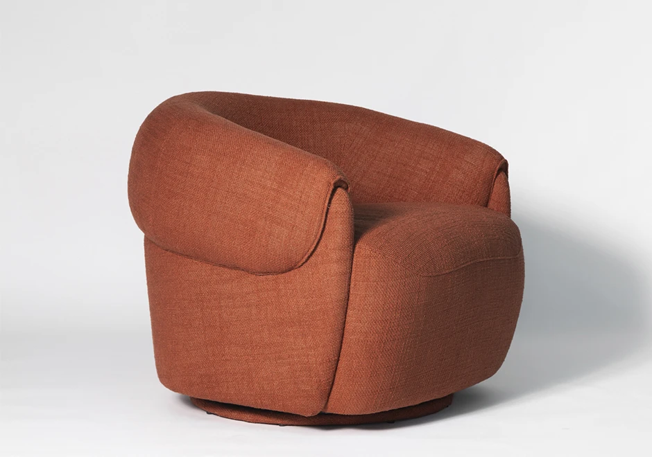 Poltrona Orca em tecido terracota, com design envolvente e volumoso. Destaque para os braços curvados e base giratória oculta, unindo conforto e sofisticação.