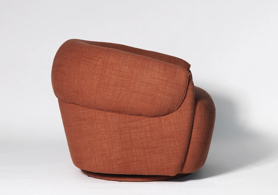 Poltrona Orca vista traseira, destacando o encosto curvado e volumoso. Revestida em tecido terracota, possui base giratória oculta para mais funcionalidade.