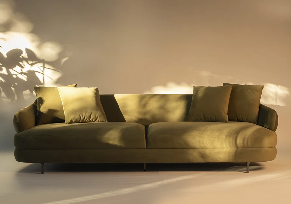 Sofá Gaudi em ambiente sofisticado, com estofamento aveludado verde e almofadas macias, destacando seu design curvo e conforto elegante