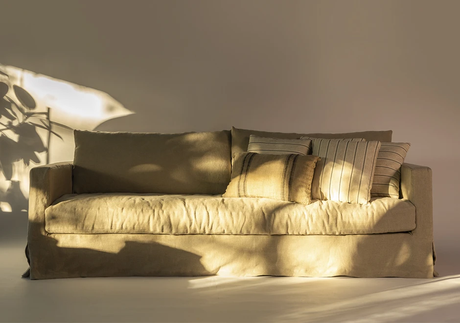 Detalhe do sofá Julia da Firma Casa, com almofadas confortáveis e tecido sofisticado, destacando aconchego e elegância.