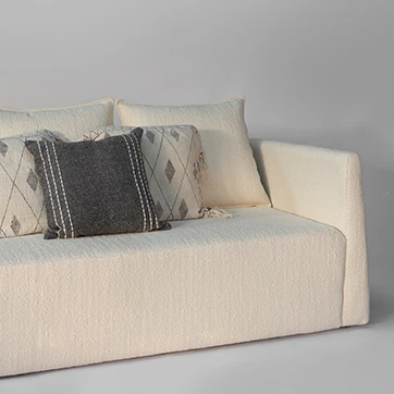 Detalhe do sofá Pedro com almofadas decorativas em tons neutros e textura sofisticada.