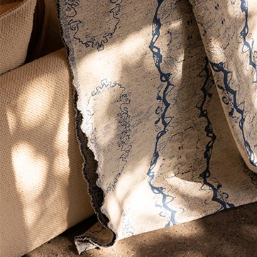 O tecido Amazônia da Fio, da Coleção Biomas, com tingimento manual, proporciona um efeito orgânico com variações ricas em texturas. Nas cores azul e cru.