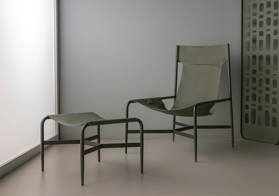 Poltrona com encosto alto e pufe da coleção Bruta, estofados em couro verde.