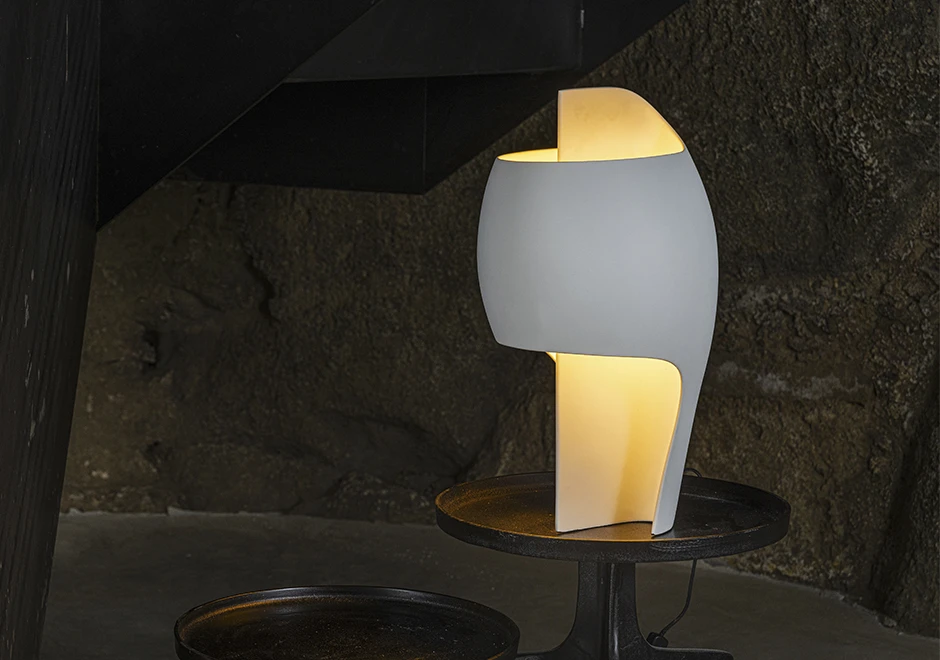 Luminária Lampe B branca, iluminando ambiente escuro.